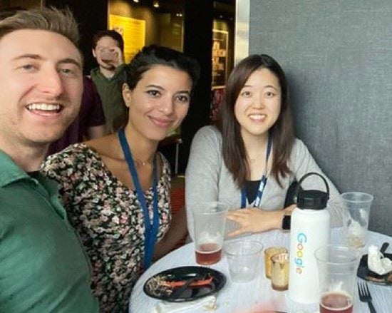 Three residents sit at a table with food and drinks